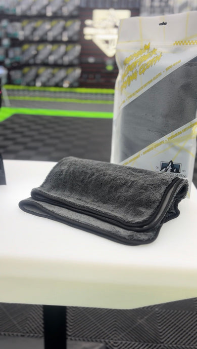 Dedicated car drying towel and double-sided buffing towel arranged beside a freshly washed and waxed vehicle.