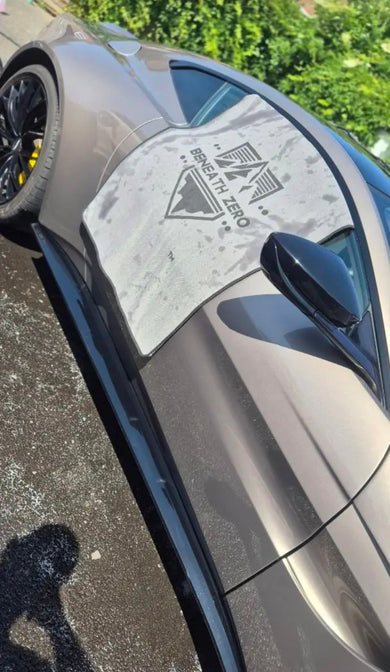 Detailer completing a fast maintenance wash on a clean car using foam, wheel brushes and microfiber drying towels.
